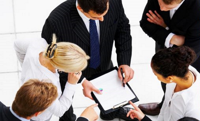 five professionals looking at a clipboard